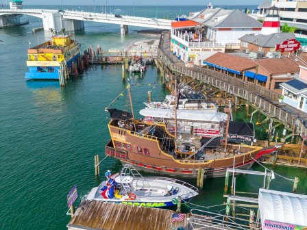 Aerial view of a pier with boats, a ship, and waterfront buildings.
