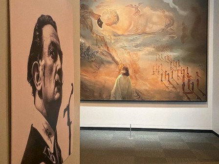 Art gallery with a surreal painting and a portrait facing away.