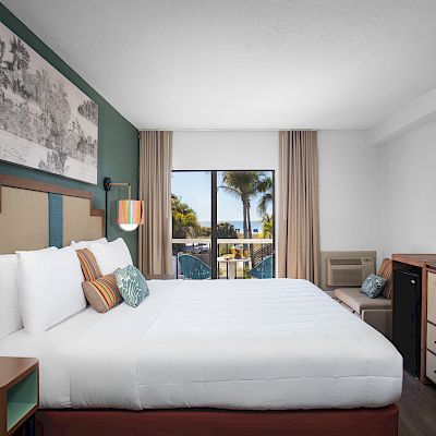 A tidy hotel room with a large bed, wall art, TV, and a glimpse of the outside view.