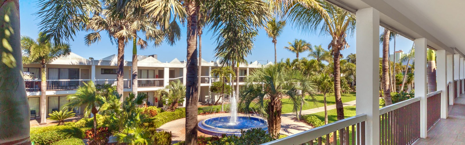 Balcony view of a tropical resort with palm trees and a hot tub.