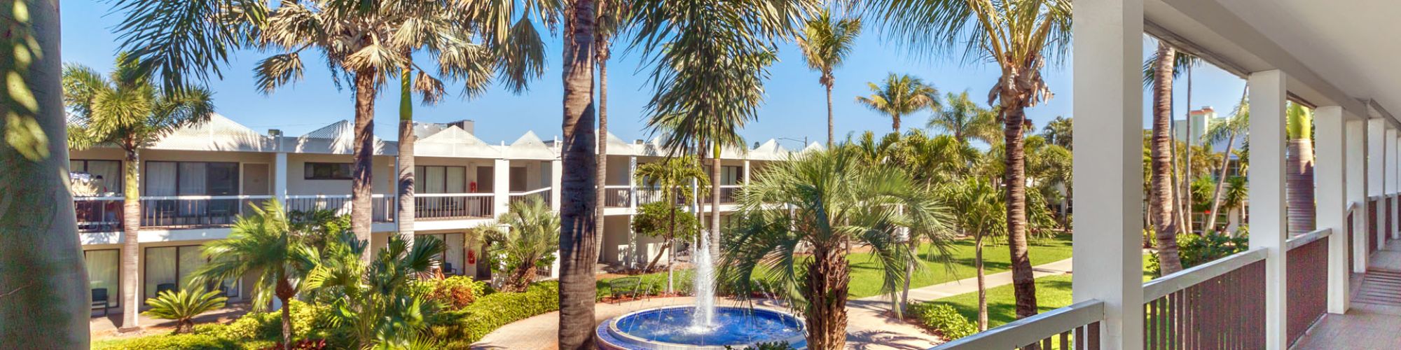 Balcony view of a tropical resort with palm trees and a hot tub.