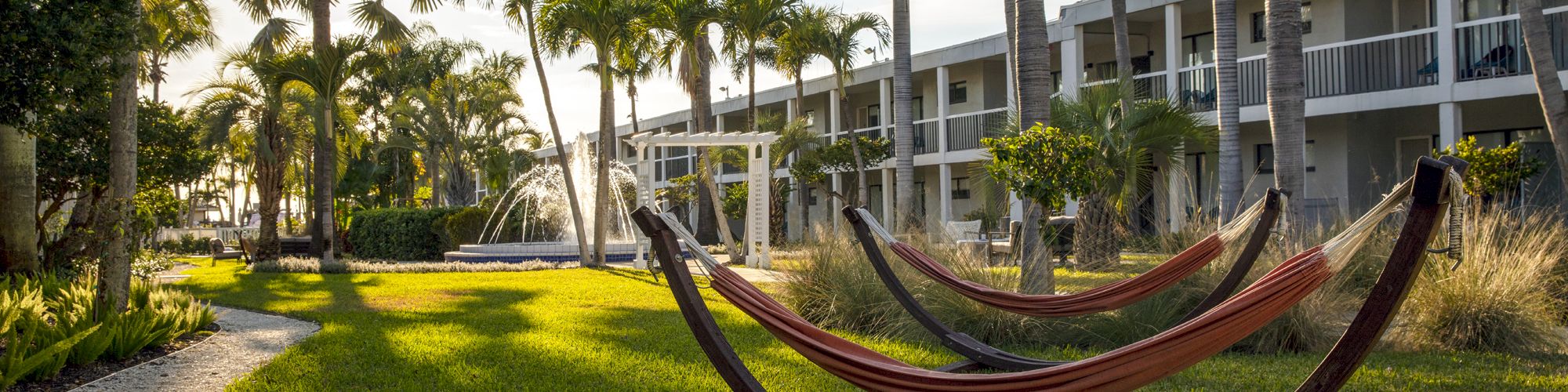 A peaceful outdoor setting with hammocks, a fountain, and an apartment building.