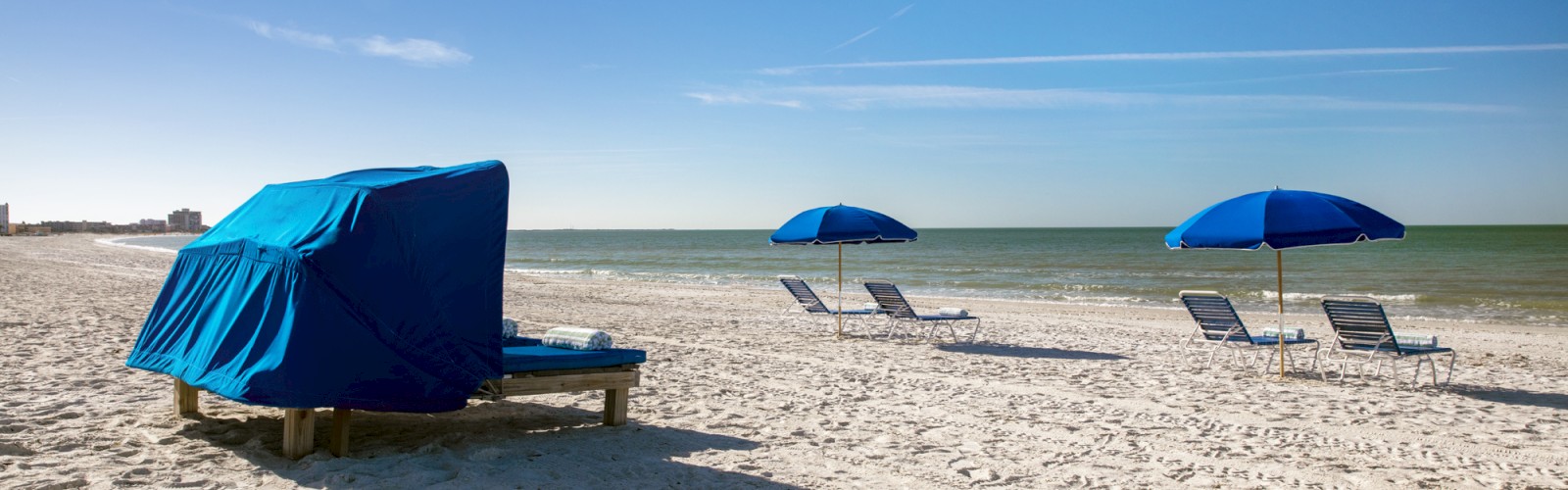 Sun loungers and umbrellas on a sandy beach with a clear sky.