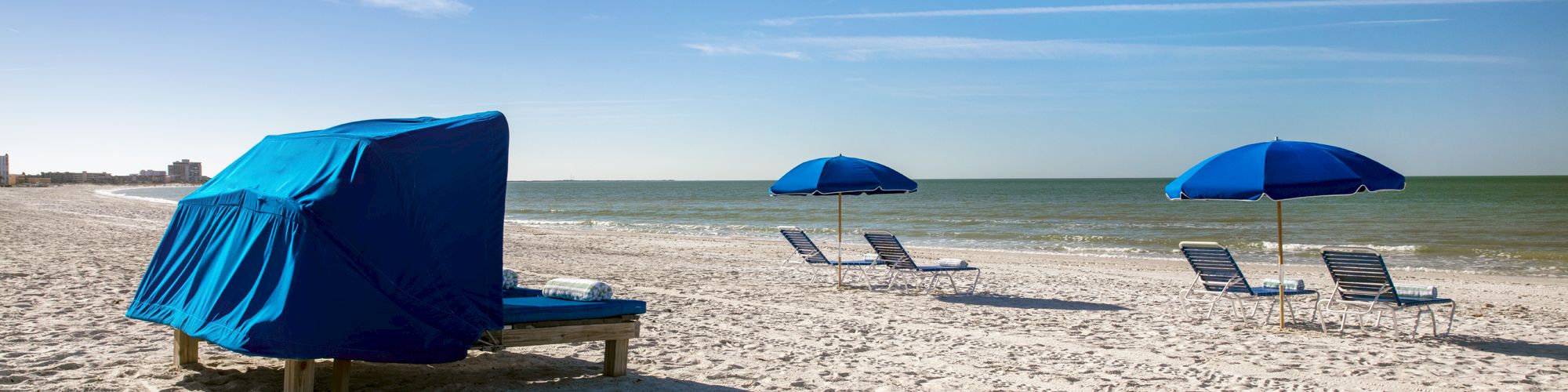 Sun loungers and umbrellas on a sandy beach with a clear sky.