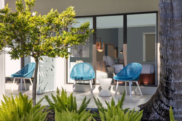 Modern terrace with blue chairs, plants, and sliding glass doors.