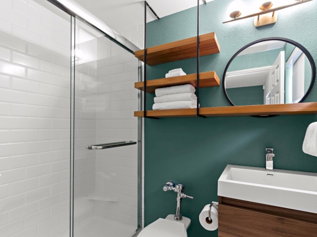 Modern bathroom interior with a shower, sink, shelves with towels, and a mirror.