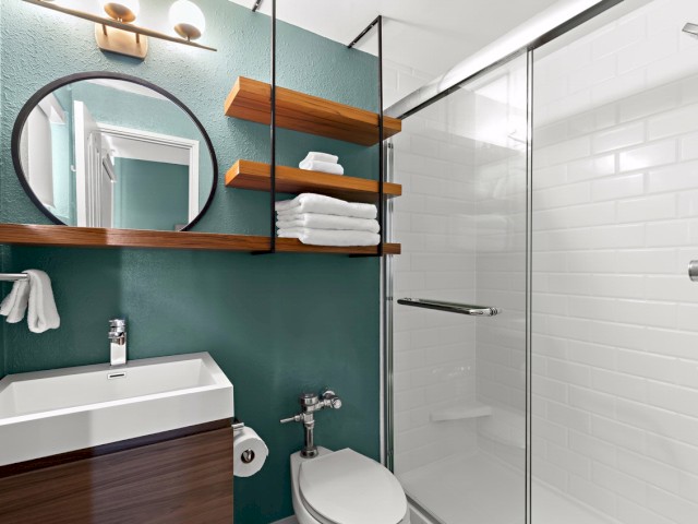 A modern bathroom with a sink, mirror, towels, and a glass shower enclosure.