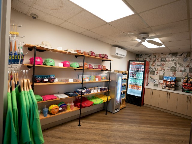 A tidy shop interior with shelves stocked with colorful products and a fridge.