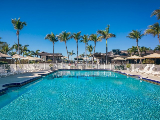 A serene pool with lounge chairs under a clear blue sky.