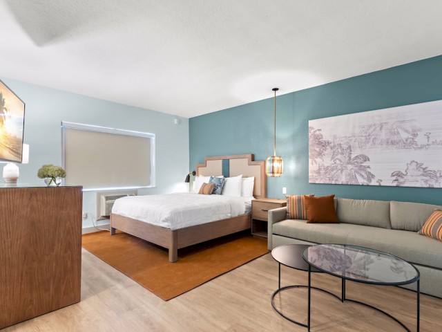 Modern bedroom with a bed, sofa, art, and stylish decor.