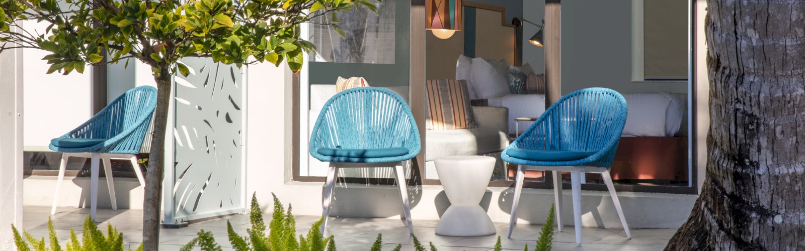 Modern patio with blue chairs, green plants, and glass doors.