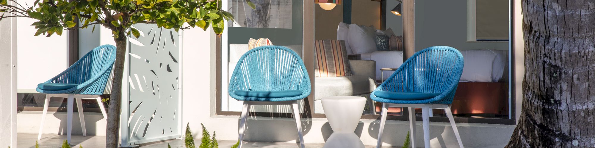 Modern patio with blue chairs, green plants, and glass doors.