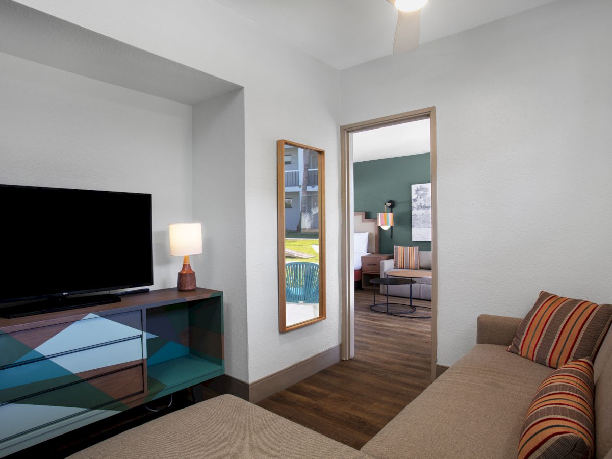 Modern living room with TV, couch, and view into a room with a table.