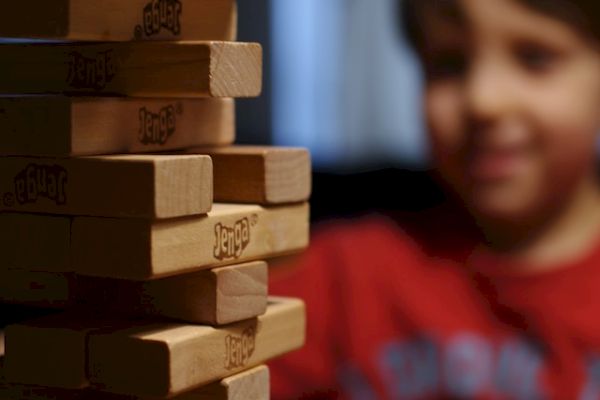 A child observes a towering Jenga game with focus and anticipation.