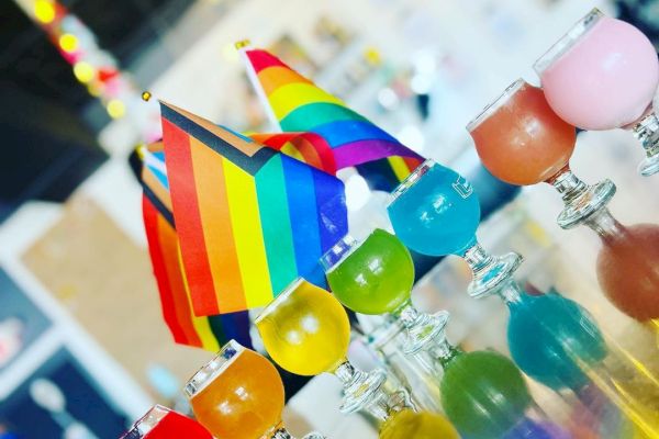Colorful balloons and a pride flag are on display, likely at an event or celebration.