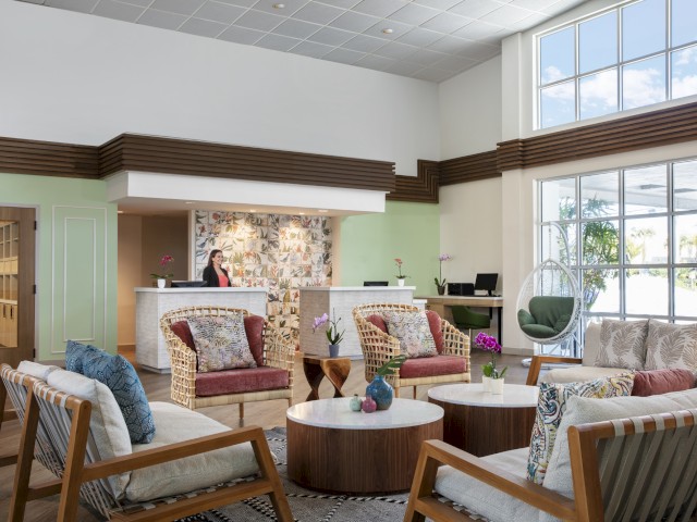 Modern lobby with furniture, reception desk, and a person in the background.