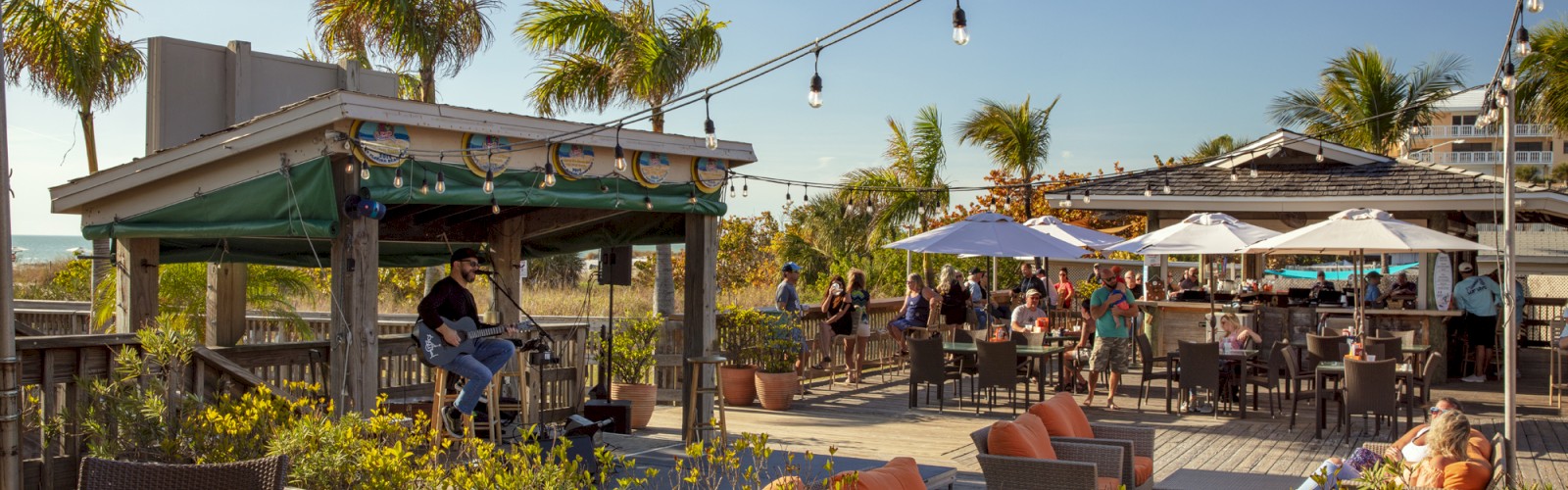 The image shows an outdoor dining area with people, furniture, and string lights.