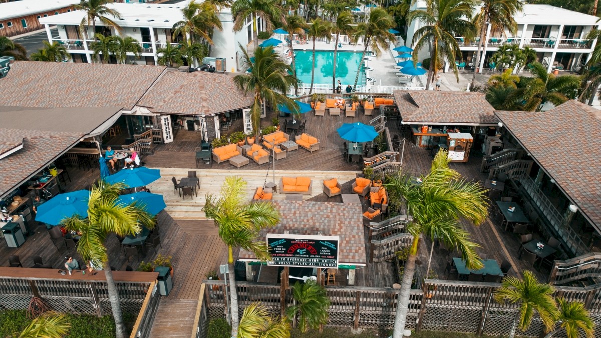 Aerial view of Beachcomber Beach Resort with pool, loungers, umbrellas, and palm trees.